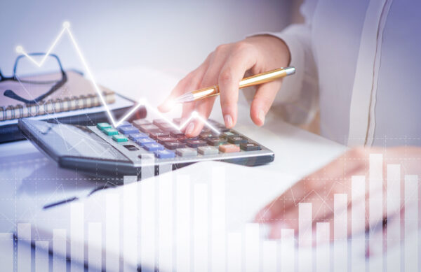 Accountant calculating profit with financial analysis graphs Accountant calculating profit with financial analysis graphs. Notebook, glasses and calculator lying on desk. Accountancy concept. Cropped view.